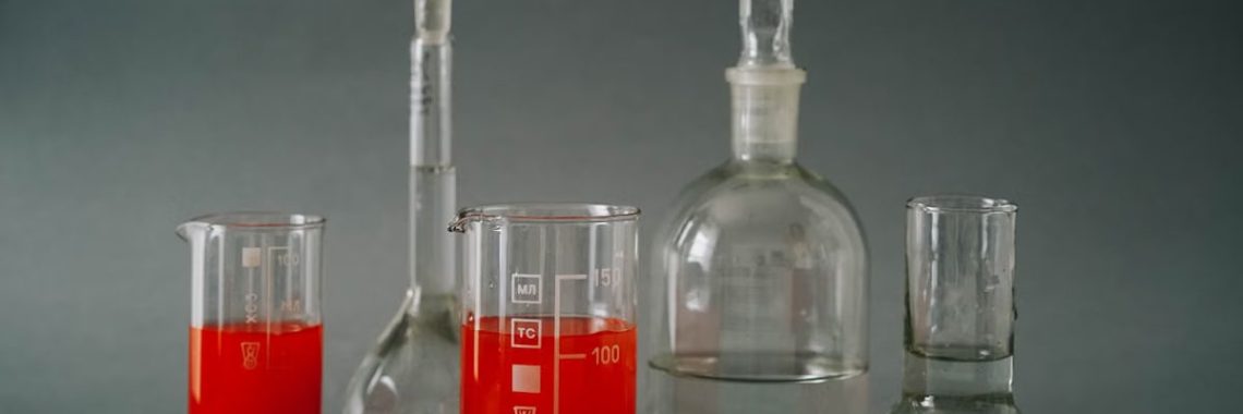 Close-up of laboratory glassware with colorful red liquids used in a chemistry lab.